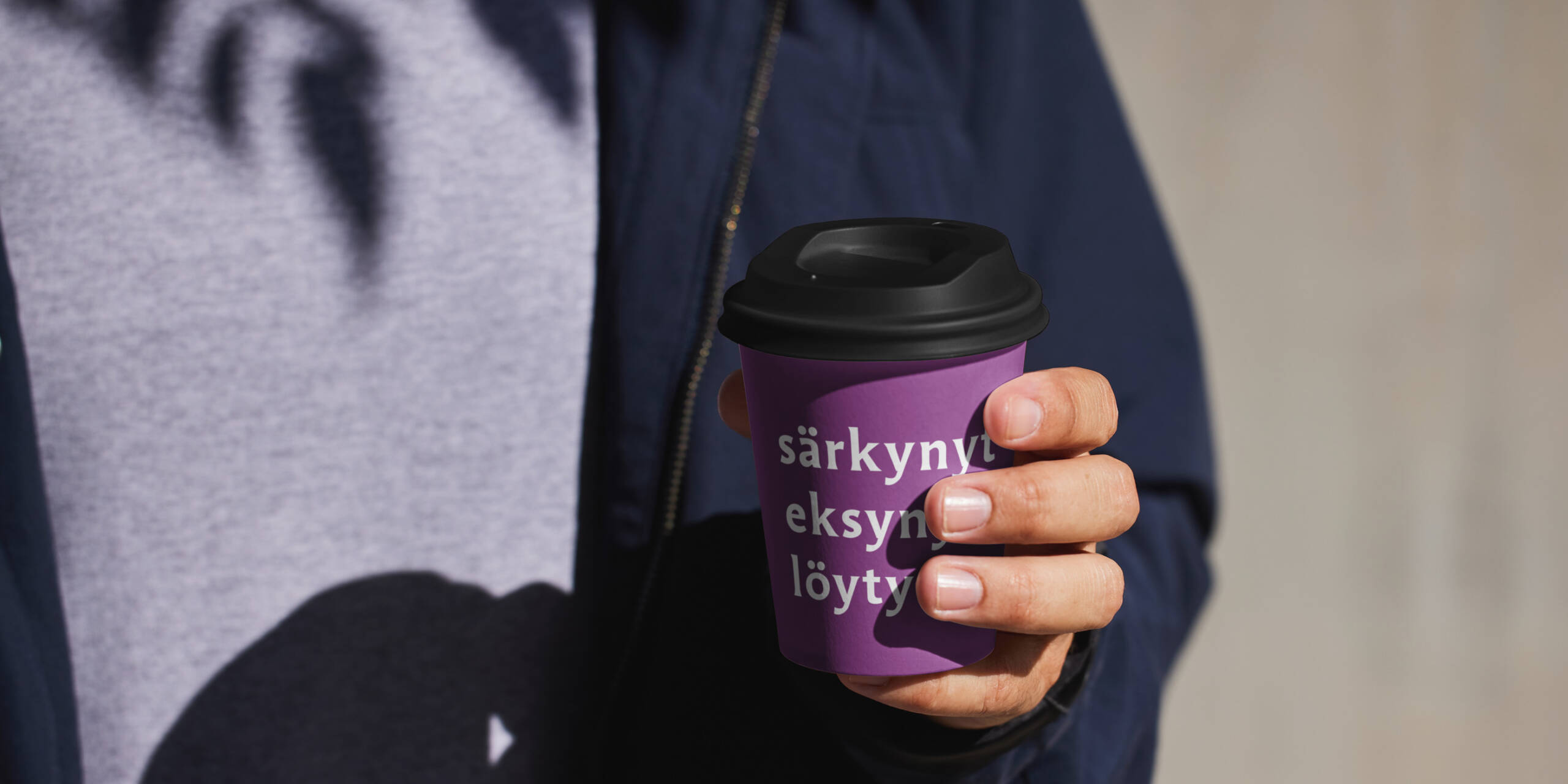 Kädessä kertakäyttö kahvimuki, jossa teksti "särkynyt, eksynyt, löytynyt".