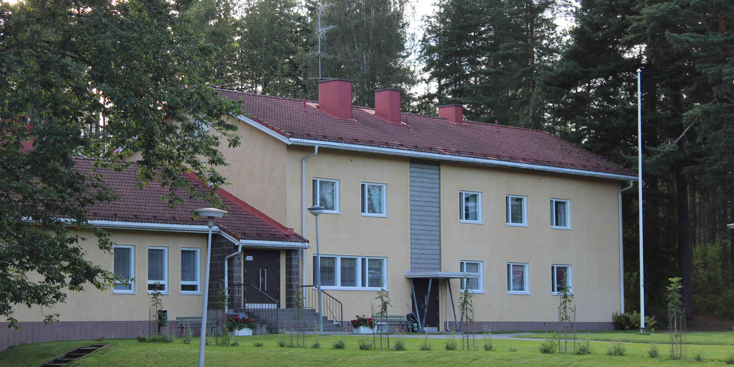 Keltainen rapattu kaksikerroksinen vanhahko talo.