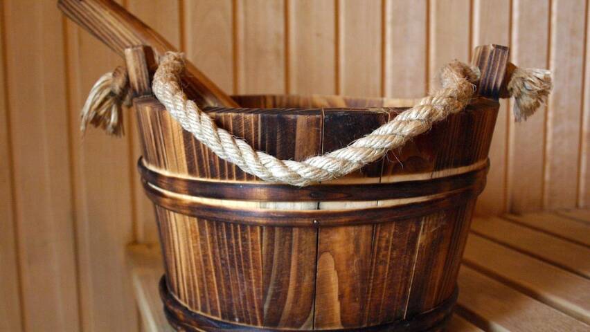 Puinen saunakiulu ja kauha lauteilla sauna­tilassa.