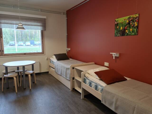Tilava huone, jossa näkyy kaksi erillistä sänkyä ja oleskelutilaa.