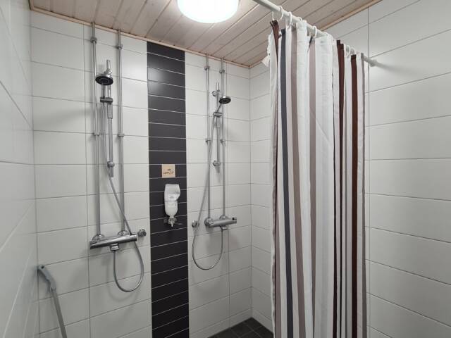 Moderni suihkutila, jossa useita suihkuja ja käytännöllinen suihkuverho.