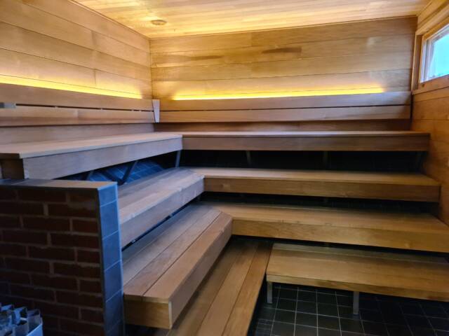 Tunnelmallinen saunatila, jossa puiset lauteet ja pehmeä valaistus rentoutumiseen.