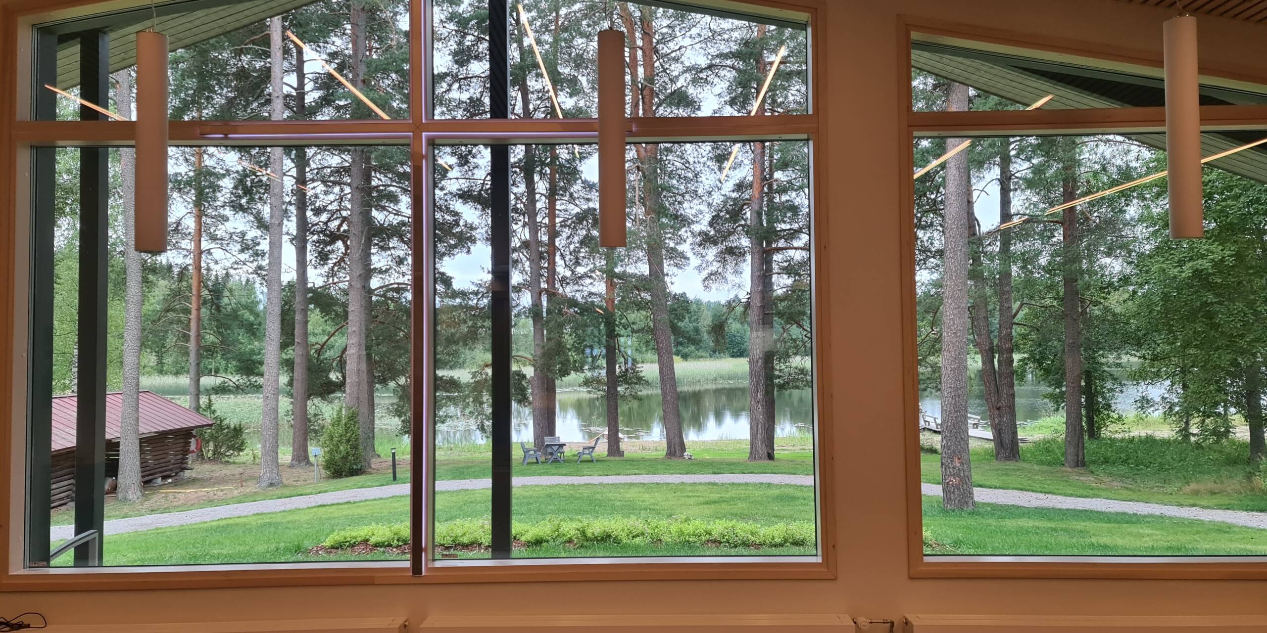 Ikkunanäkymä pihapiiriin ja järvelle, rauhallinen maisema tuo tilaan levollisen tunnelman.