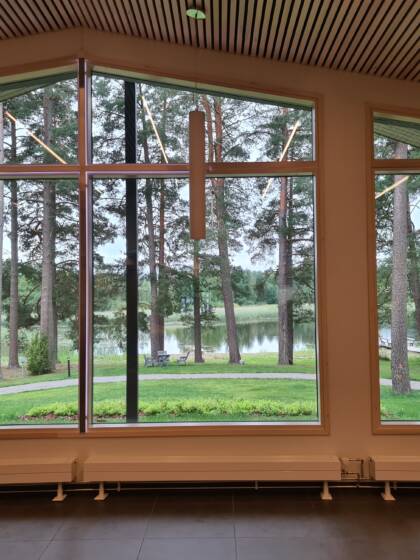 Ikkunanäkymä pihapiiriin ja järvelle, rauhallinen maisema tuo tilaan levollisen tunnelman.