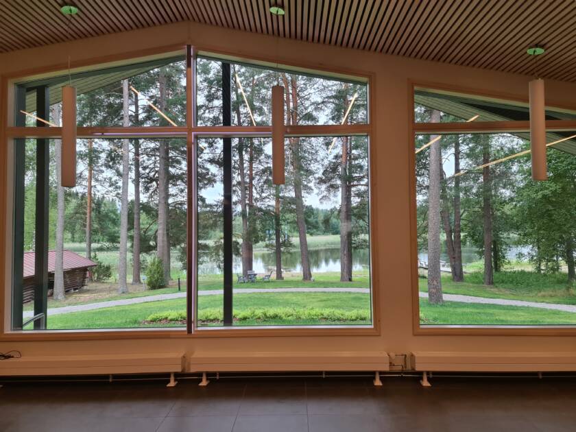 Ikkunanäkymä pihapiiriin ja järvelle, rauhallinen maisema tuo tilaan levollisen tunnelman.