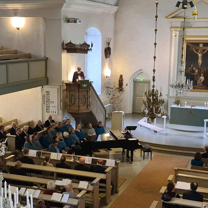 Piispa Matti Repo saarnaa saarnatuolissa ja seurakunta kuuntelee.