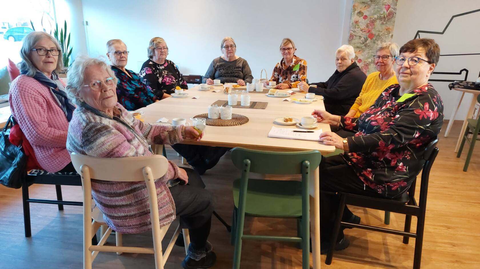 Joukko iäkkäämpiä ihmisiä pöydän ääressä.